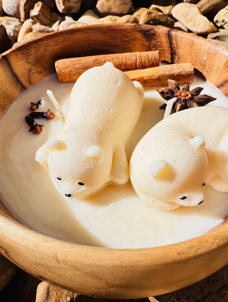Polar bear candle in a round wooden bowl photographed on stones