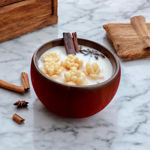 Candle in a brown bowl with cream-colored flower decorations